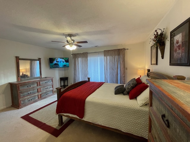 carpeted bedroom featuring ceiling fan and a textured ceiling