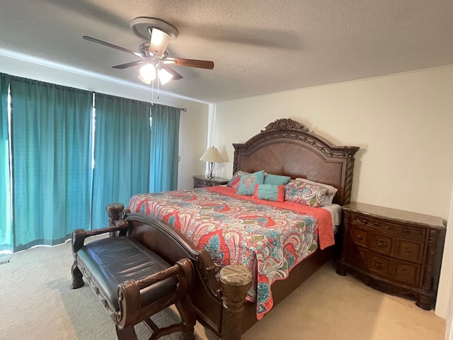 bedroom with a textured ceiling, light colored carpet, and ceiling fan