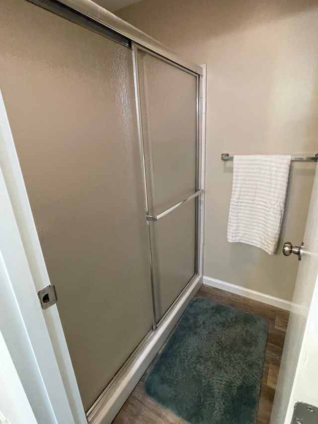 bathroom with an enclosed shower and wood-type flooring