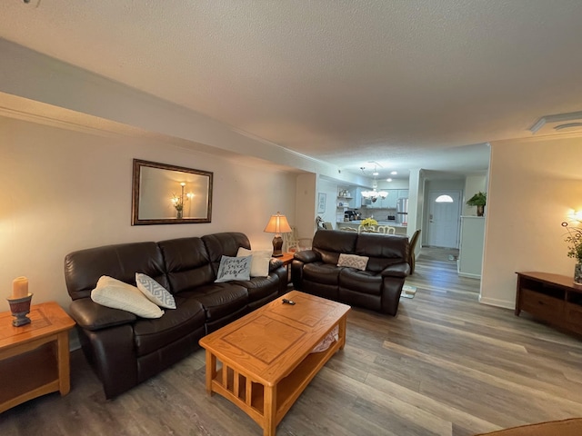 living room featuring a chandelier, wood-type flooring, and a textured ceiling