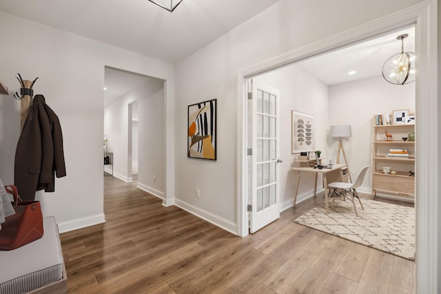 hallway featuring hardwood / wood-style flooring and a notable chandelier