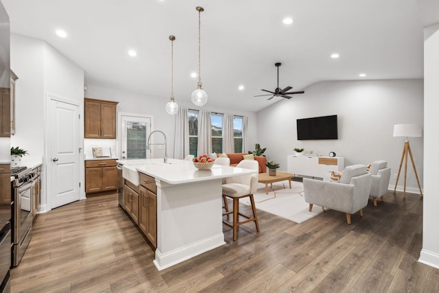 kitchen featuring vaulted ceiling, a kitchen bar, gas range, dark wood-type flooring, and a center island with sink