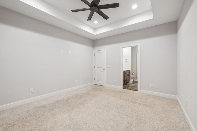 unfurnished bedroom with connected bathroom, a raised ceiling, and carpet