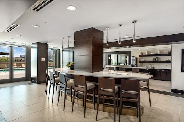 kitchen with dark brown cabinetry, sink, pendant lighting, a breakfast bar area, and light tile patterned floors