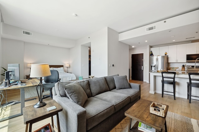 bedroom featuring stainless steel fridge and light hardwood / wood-style flooring