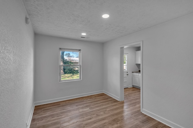 spare room featuring light hardwood / wood-style floors and a textured ceiling