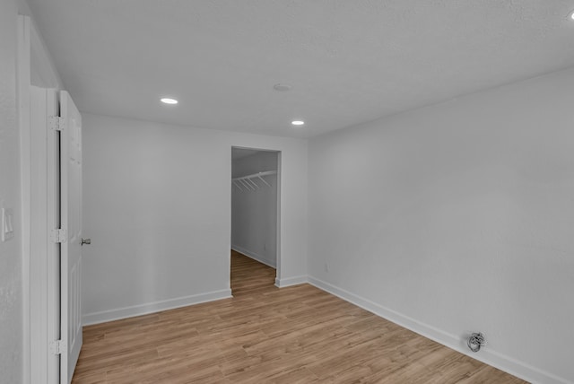 unfurnished bedroom with a closet, a spacious closet, and light wood-type flooring