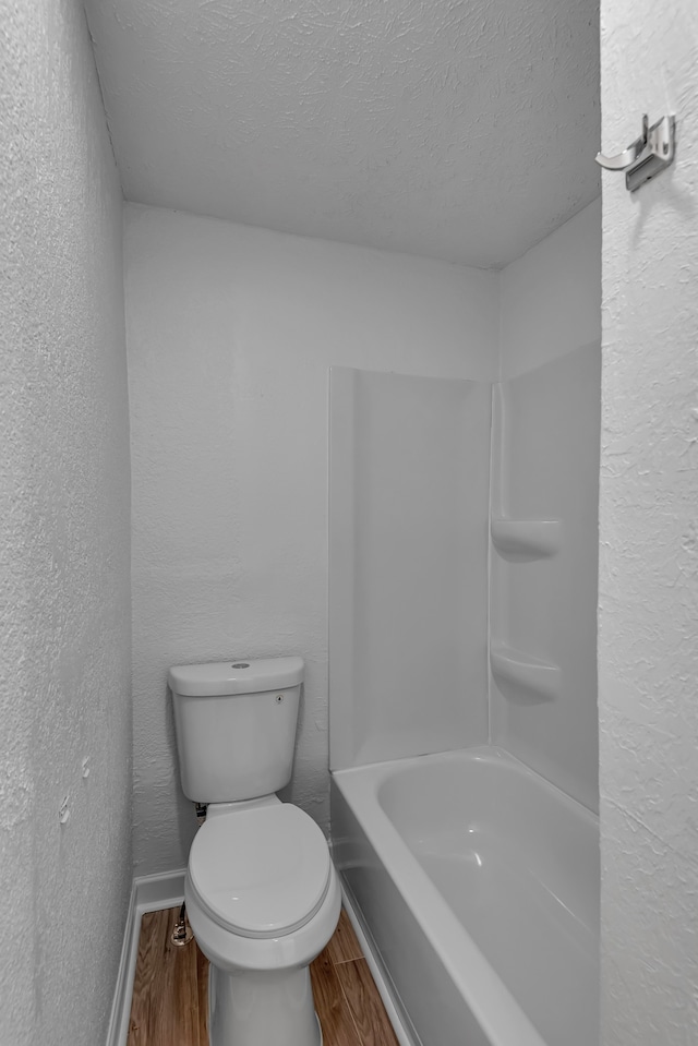 bathroom with a textured ceiling, hardwood / wood-style flooring, and toilet