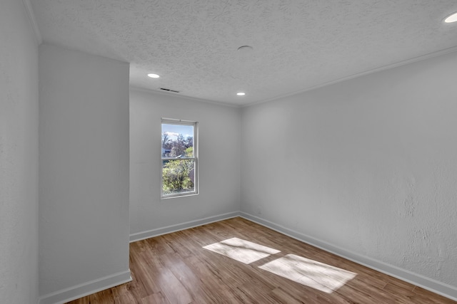 empty room with light hardwood / wood-style flooring, ornamental molding, and a textured ceiling