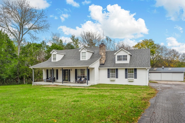 cape cod house featuring an outbuilding, a front lawn, covered porch, and a garage