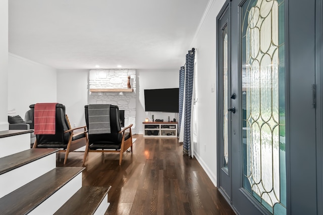 entryway with a fireplace, ornamental molding, and dark wood-type flooring