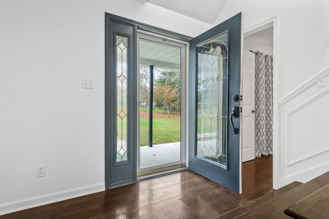 doorway to outside with a textured ceiling, dark hardwood / wood-style floors, vaulted ceiling, and a wealth of natural light