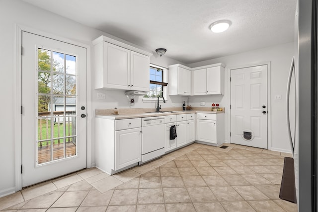 kitchen with white cabinets, stainless steel refrigerator, sink, light tile patterned floors, and dishwasher