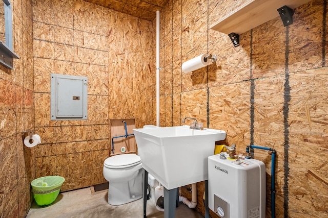 bathroom featuring concrete flooring, electric panel, toilet, and sink