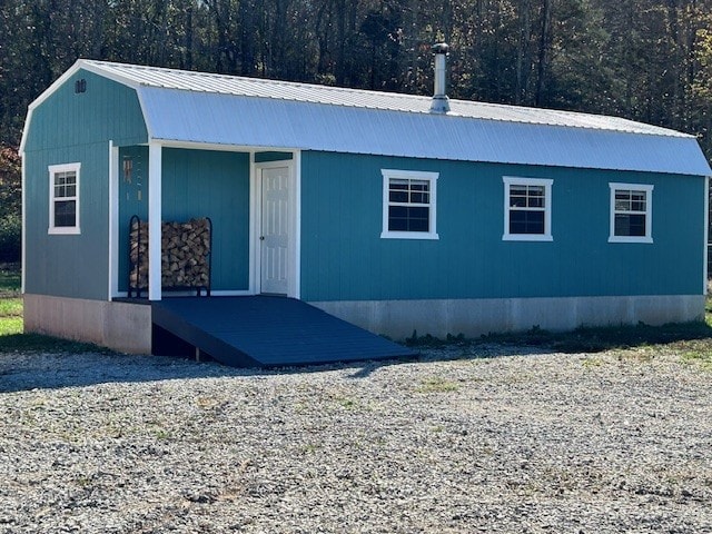 view of front of property featuring metal roof, a forest view, and a gambrel roof