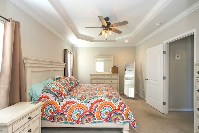 carpeted bedroom with a tray ceiling, ceiling fan, and crown molding