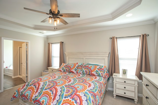 carpeted bedroom with ensuite bath, ornamental molding, ceiling fan, and a tray ceiling