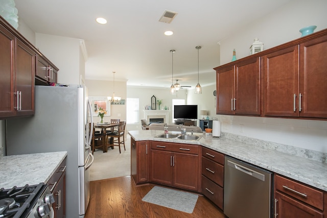 kitchen featuring sink, hanging light fixtures, dark hardwood / wood-style floors, ceiling fan with notable chandelier, and appliances with stainless steel finishes