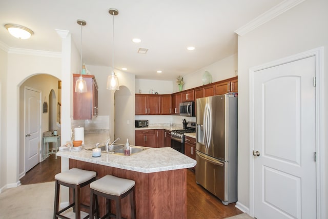 kitchen featuring dark wood-type flooring, hanging light fixtures, kitchen peninsula, a kitchen bar, and appliances with stainless steel finishes