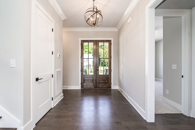 foyer entrance with ornamental molding, french doors, dark wood-type flooring, and an inviting chandelier