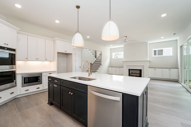 kitchen featuring white cabinetry, sink, an island with sink, pendant lighting, and appliances with stainless steel finishes