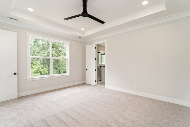 empty room with light carpet, a tray ceiling, ceiling fan, and crown molding