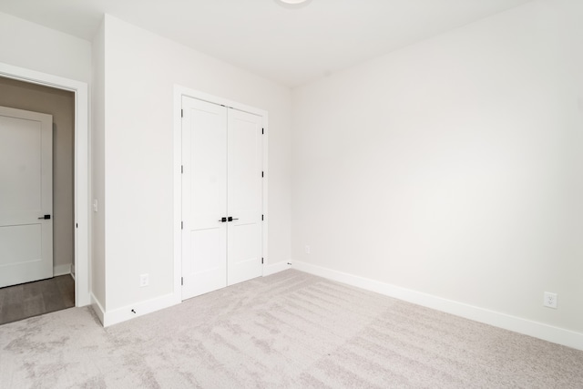 unfurnished bedroom with light carpet and a closet