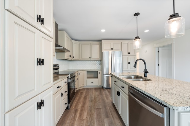 kitchen featuring sink, hanging light fixtures, wood-type flooring, a kitchen island with sink, and appliances with stainless steel finishes