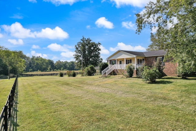 view of front of property featuring a front lawn, covered porch, and a rural view