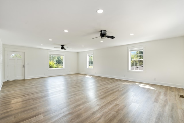 empty room with a wealth of natural light, ceiling fan, and light hardwood / wood-style floors