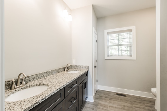 bathroom with vanity, toilet, and hardwood / wood-style flooring