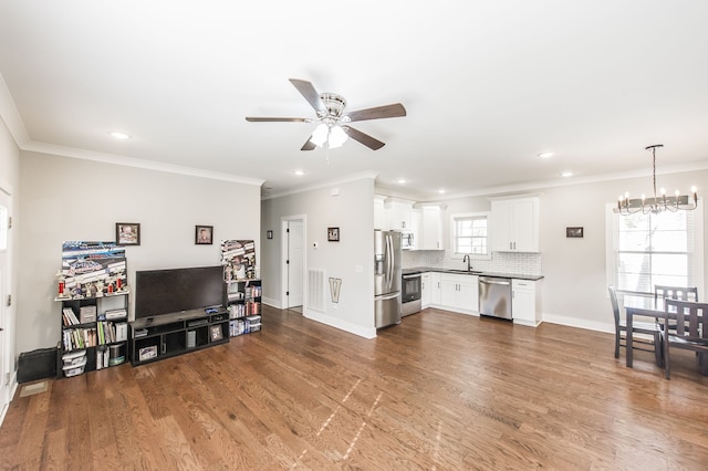 living room with ceiling fan with notable chandelier, sink, crown molding, and dark hardwood / wood-style floors