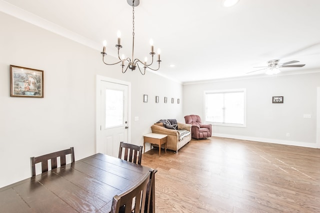 dining room featuring ceiling fan with notable chandelier, wood-type flooring, and crown molding