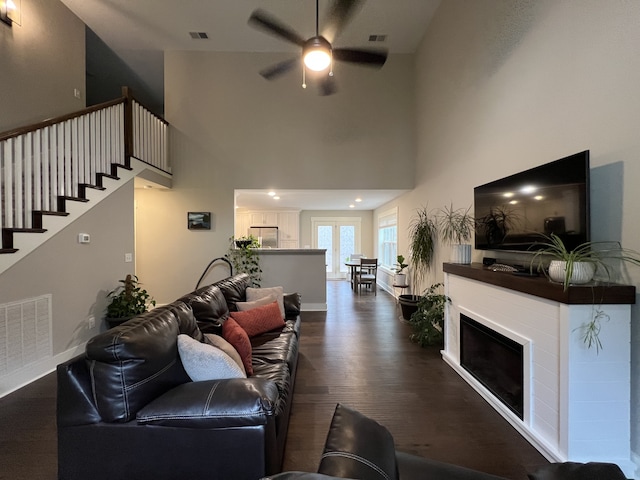 living room featuring ceiling fan, dark hardwood / wood-style flooring, and a towering ceiling