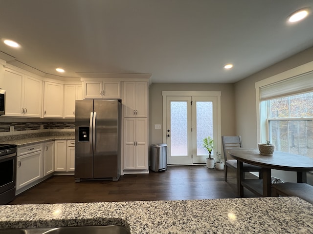 kitchen featuring stainless steel fridge, light stone countertops, white cabinetry, and a healthy amount of sunlight