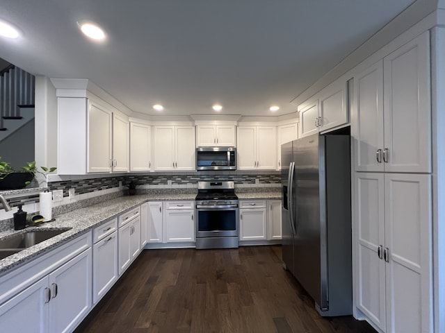 kitchen featuring light stone countertops, dark hardwood / wood-style flooring, backsplash, stainless steel appliances, and white cabinetry