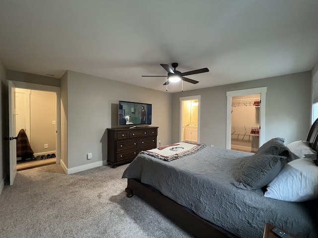 bedroom with a closet, a walk in closet, light colored carpet, and ceiling fan