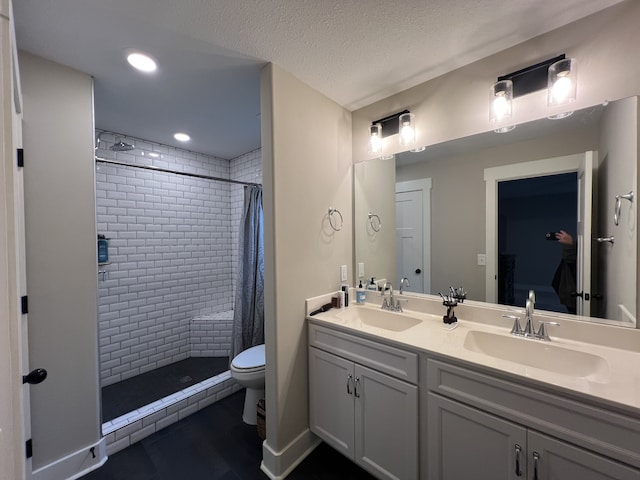 bathroom with a textured ceiling, vanity, toilet, and walk in shower