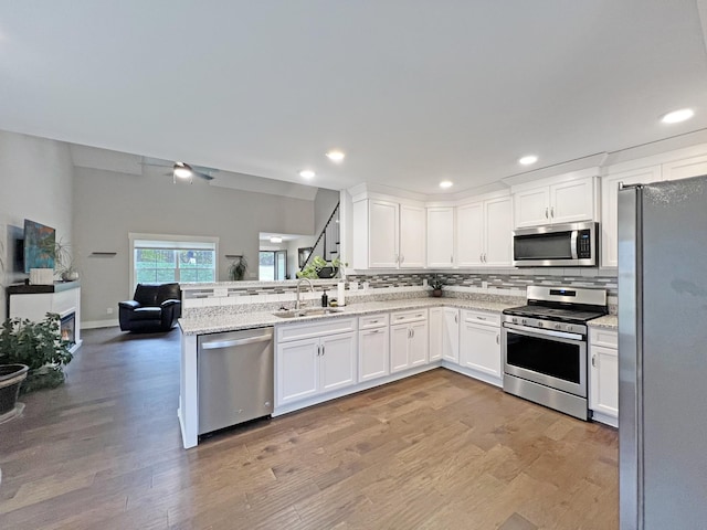731 Hogan Rd, Clarksville, TN 37043 - kitchen featuring stainless steel appliances, a sink, open floor plan, tasteful backsplash, and white cabinets