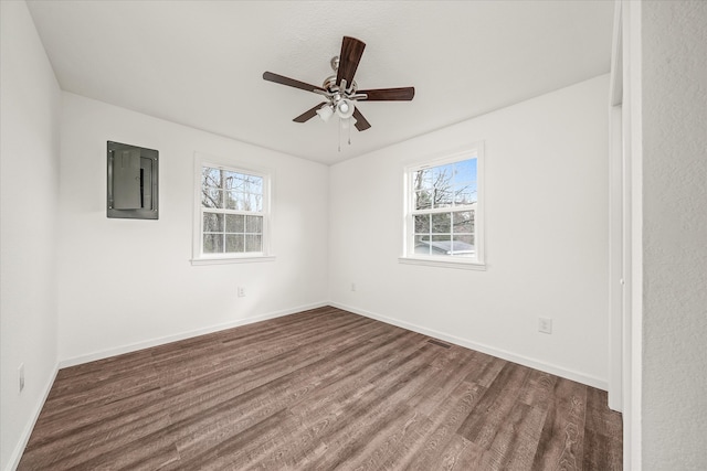 unfurnished room with electric panel, a wealth of natural light, dark hardwood / wood-style flooring, and ceiling fan