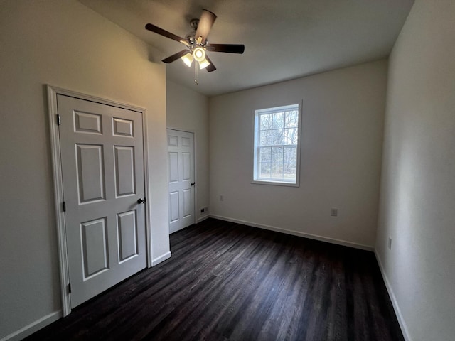 unfurnished bedroom with ceiling fan and dark wood-type flooring