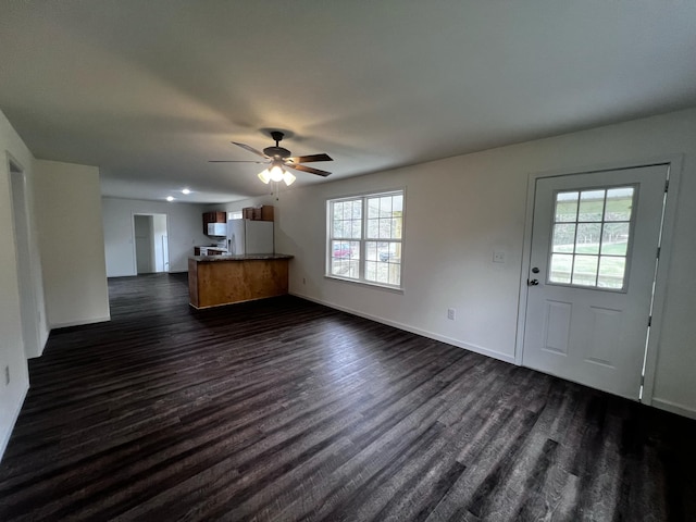 unfurnished living room with ceiling fan, plenty of natural light, and dark hardwood / wood-style floors