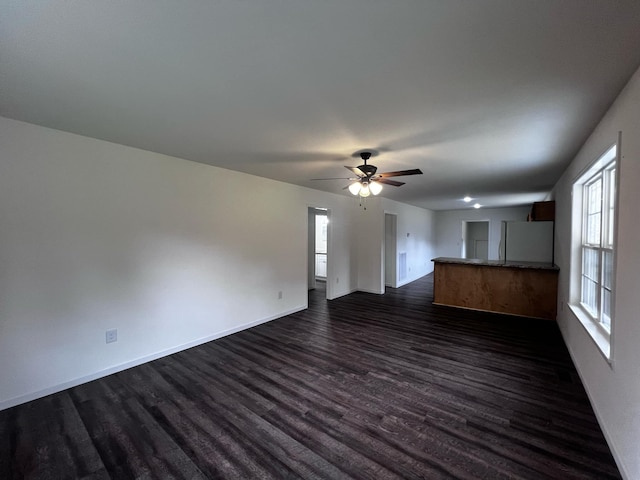 unfurnished living room featuring ceiling fan and dark hardwood / wood-style flooring