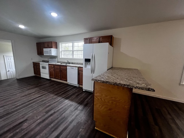 kitchen featuring light stone countertops, sink, dark wood-type flooring, kitchen peninsula, and white appliances