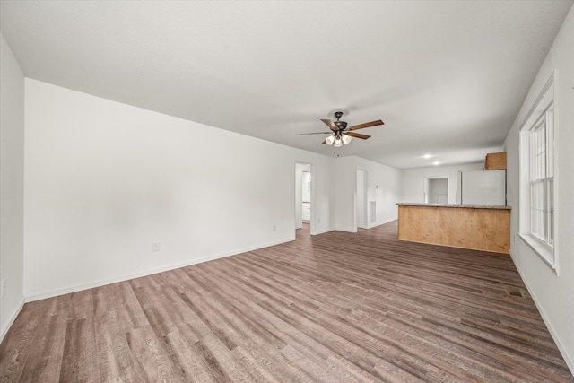 unfurnished living room featuring a wealth of natural light, ceiling fan, and dark hardwood / wood-style floors