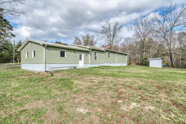 back of house featuring a lawn and a storage shed