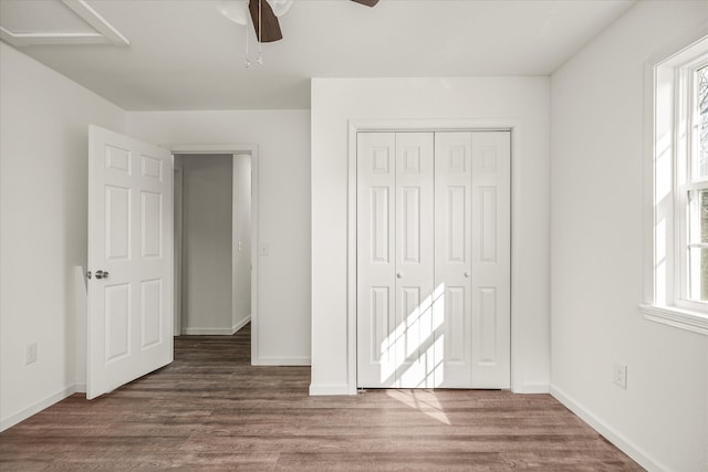 unfurnished bedroom featuring a closet, ceiling fan, multiple windows, and dark hardwood / wood-style flooring