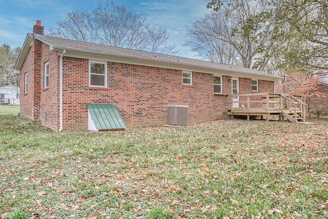 rear view of property featuring a yard, a wooden deck, and cooling unit