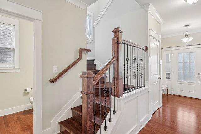 staircase with wood-type flooring, plenty of natural light, and ornamental molding