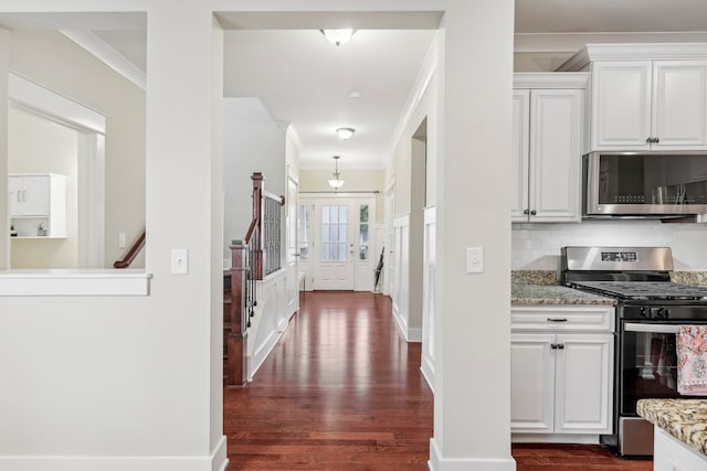 kitchen featuring light stone countertops, white cabinetry, stainless steel appliances, dark hardwood / wood-style flooring, and decorative backsplash